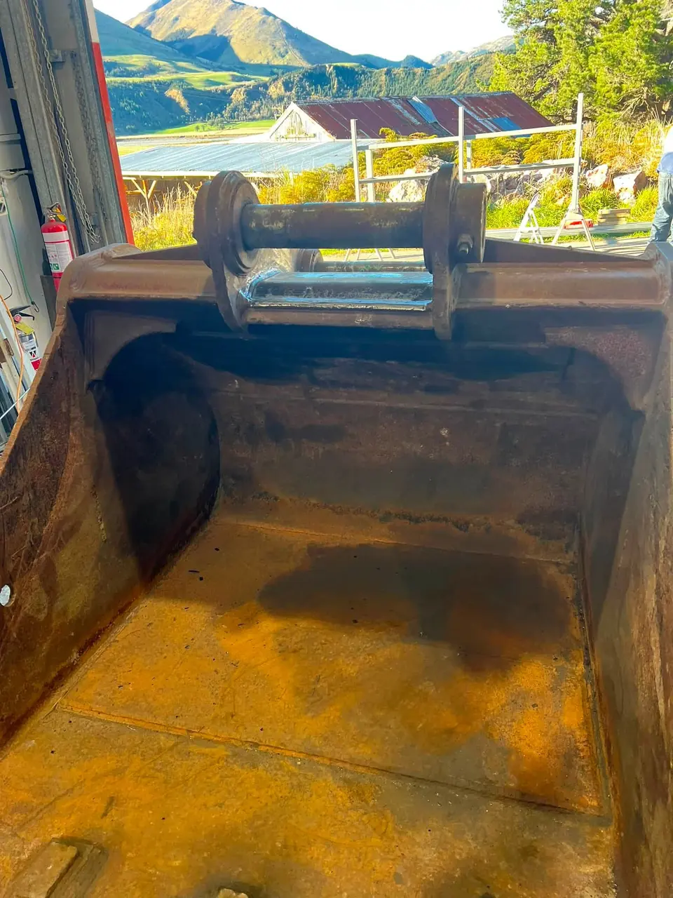 Inside of a large bucket after painting, looking out through the workshop door